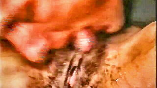Couple on a patterned bedspread in an explicit scene