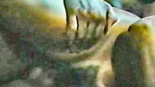 Couple on a made bed in an explicit scene