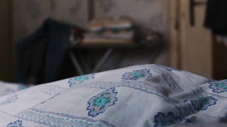 Couple on a made bed in an explicit scene