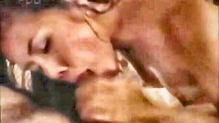 Couple on a made bed in an explicit scene