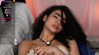 Solo performer with a toy on rumpled bedsheets