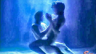 Couple on a made bed in an explicit scene