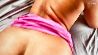 Solo performer with a toy on rumpled bedsheets