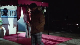 Couple on a patterned bedspread in an explicit scene